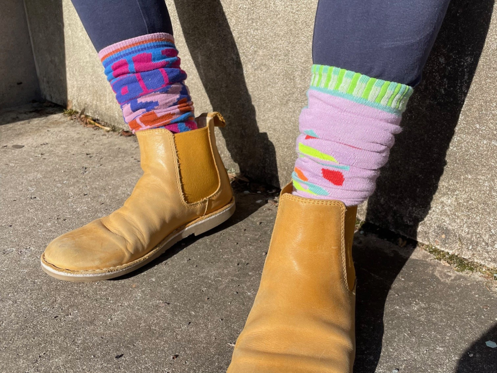 Zwei Füße mit hellbrauen Schuhen und bunten Socken.