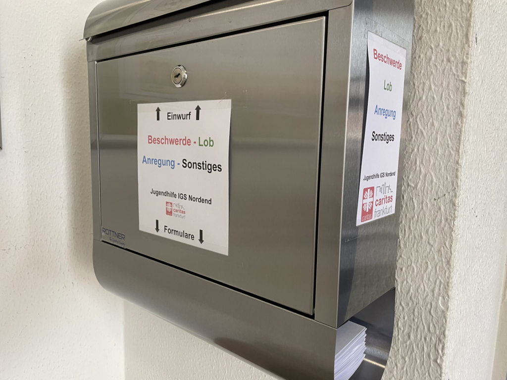 Ein Blick von der Seite auf einen Metallbriefkaasten. An der Seite und an der Vorderfront hängen Schilder mit der Aufschrift: Beschwerde, Lob, Anregung, Sonstiges