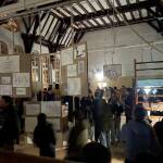 Die hohe Turnhalle mit den Holzstreben am Dach ist gefüllt mit Stellwänden, Klettergestellen und sonstigen Turngeräten auf denen Kunstwerke angebracht sind.